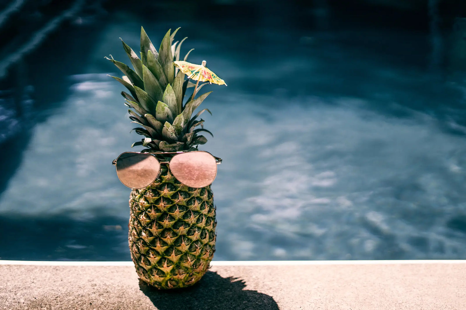 Pineapple wearing sunglasses by a poolside, tropical summer vibe